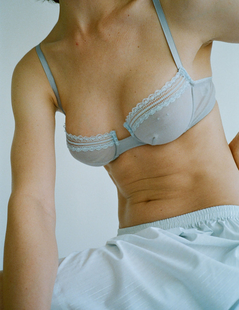 a model in the araks cotton crepe chloe underwire bra in mist grey with blue lace