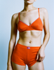 A model in the araks organic cotton antonia bralette in marmalade orange