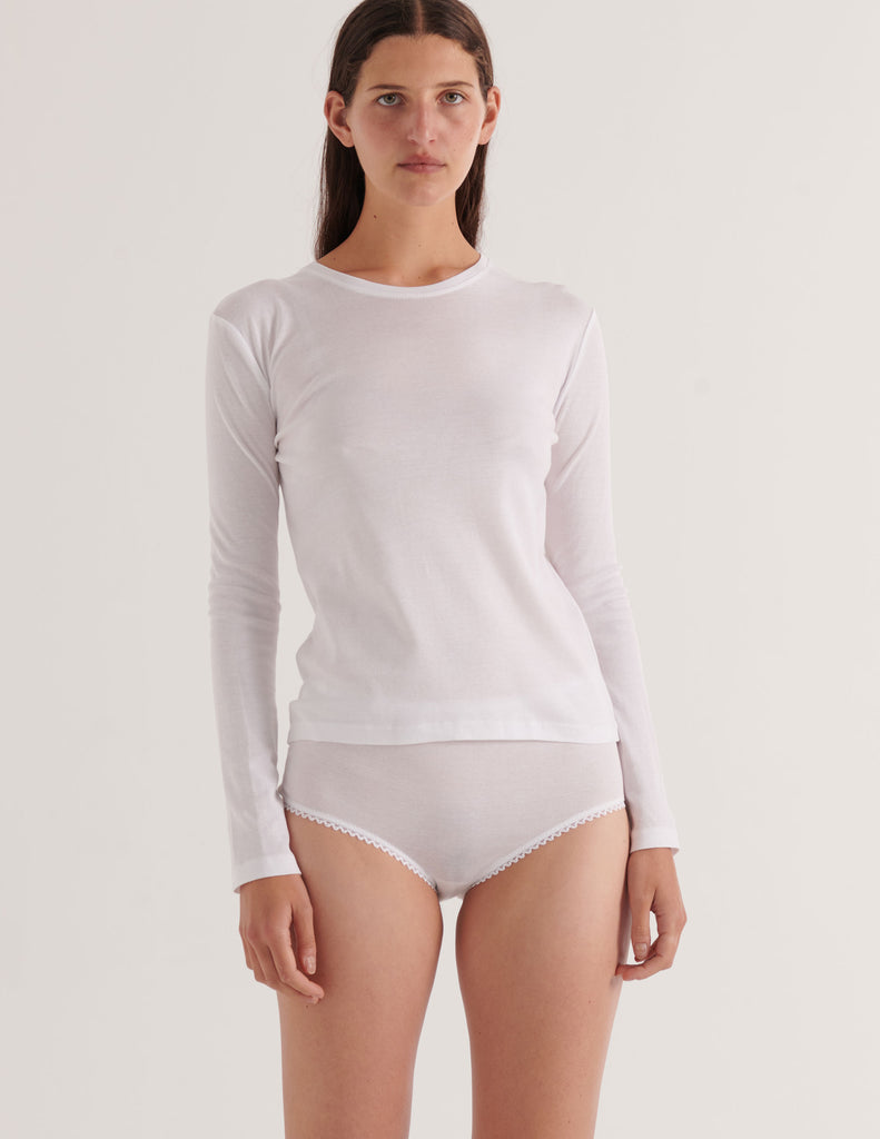 A model in the araks organic cotton sabine long sleeve shirt and isabella panty in white