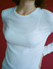 Person wearing an Araks 100% Organic Cotton white long-sleeve tee with white panties against a red background