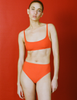 A model in the araks quinn bikini top and tolle bikini bottom in papaya orange