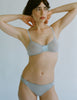 a model in the araks silk and cotton uma bralette and harriet panty in mist blue grey
