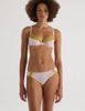 A model in the araks chloe underwire bra and sonja panty in confection pink with chartreuse lace trim