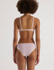 A model in the araks chloe underwire bra and sonja panty in confection pink with chartreuse lace trim