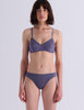 A model wearing Araks Antonia bralette and isabella panty in Violette against a light gray studio background.