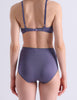 A model wearing Araks Mabel hipster and Antonia bralette in Violette posed against a plain light gray background.