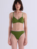 A model posing against a white background while wearing the isabella bralette and matching green thong in the shade moss.