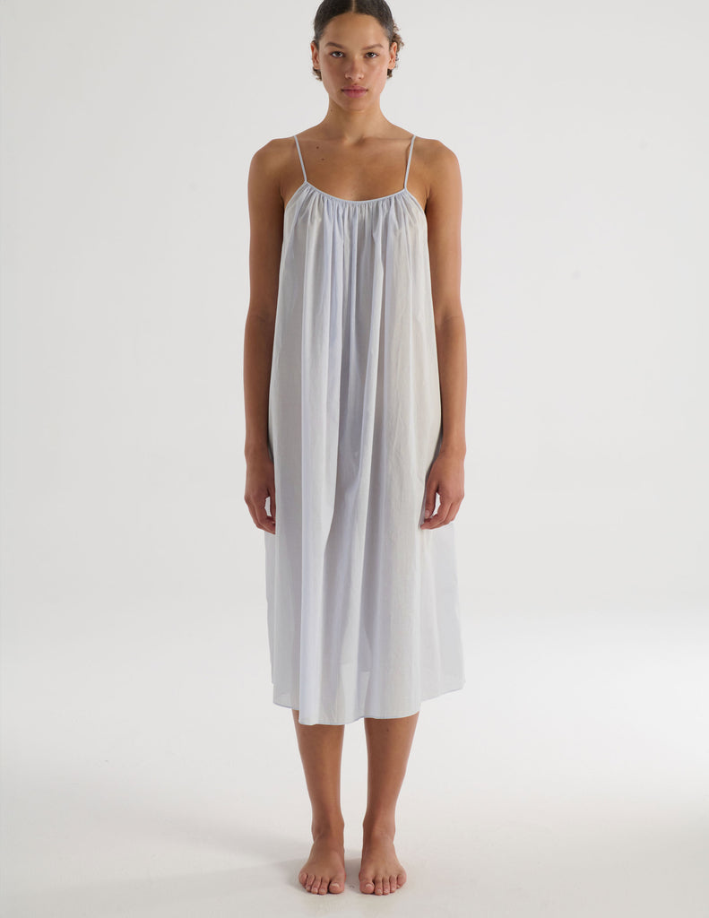 Woman wearing a light gray Raffaela slip dress on a white background