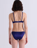 A model posing against a white background while wearing  the Gita bra in the shade starling.