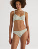 A model in the araks tamara bralette and tris panty in caledonia green