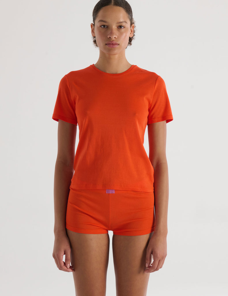 A model in the araks tavi short sleeve and presley short in organic cotton in marmalade orange