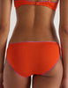 close up of Person wearing an Araks orange organic cotton Isabella Panty set on a white background