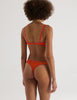Back of Person wearing an Araks orange organic cotton Antonia Bralette and Stella thong set on a white background