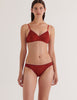 A model in the araks organic cotton antonia bralette and isabella panty in clay red