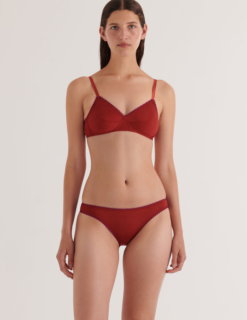 A model in the araks organic cotton antonia bralette and isabella panty in clay red