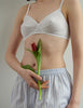 woman wearing white organic cotton antonia bra by a white wall 