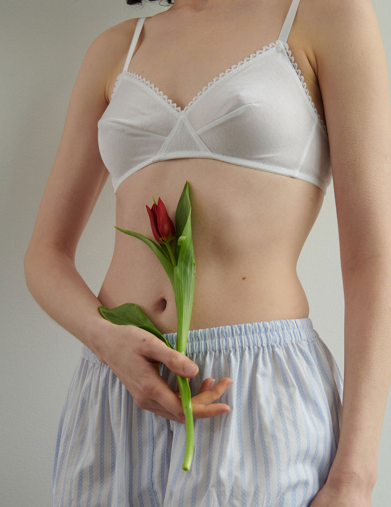 woman wearing white organic cotton antonia bra by a white wall 