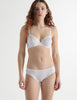 Front view of woman wearing white organic cotton isabella panty with white trim, and matching bra.