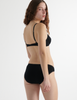 Back view of woman wearing black organic cotton isabella panty with black trim, and matching bralette.