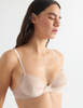 Detail image of model wearing araks organic cotton sand colored sofia underwire bra with matching trim. 