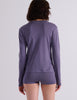 A model wearing a Sabine long sleeve top and Presley shorts in Violette, standing against a plain light gray wall.