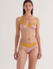 A model in the araks silk beatrice bralette and aaron panty in empress purple and yellow