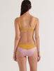 A model in the araks silk beatrice bralette and aaron panty in empress purple and yellow