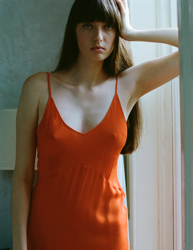 A model posing in a red silk Araks slip.