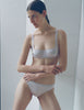A model wearing the araks silk gita underwire bra and gwyneth panty in fairy lavender with her arms crossed