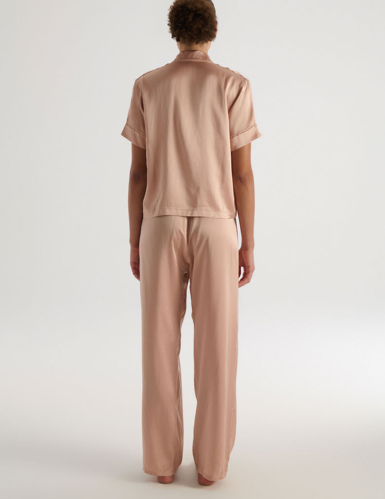A model in the araks shelby pajama top and ally pajama pant in shiny silk charmeuse