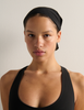 Person wearing a black swim cap and black bathing suit against a plain background