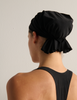 Person wearing a black swim cap and black bathing suit against a plain background