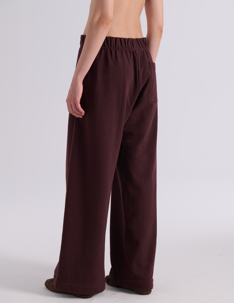A model shown from the back wearing the Araks Vero wide-leg sweatpants in the shade Mill color, against a light gray studio background.