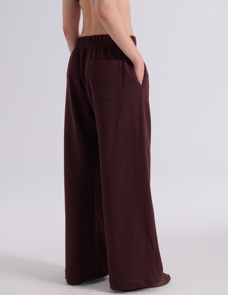 A model shown from the back wearing the Araks Vero wide-leg sweatpants in the shade Mill color, against a light gray studio background.