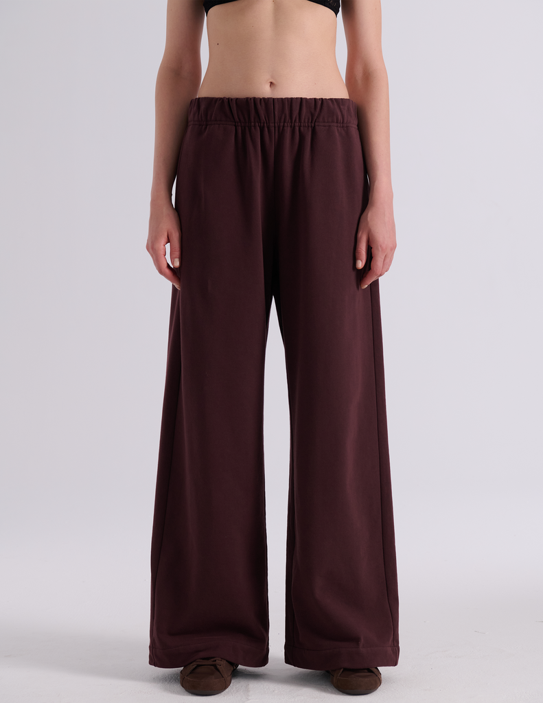 A model shown from the back wearing the Araks Vero wide-leg sweatpants in the shade Mill color, against a light gray studio background.