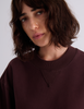 A close-up of a model wearing the Araks Valerie crewneck sweatshirt in the shade Mill.