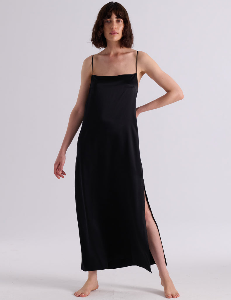 A woman modeling the Araks Vika slip in Black against a light gray studio background.