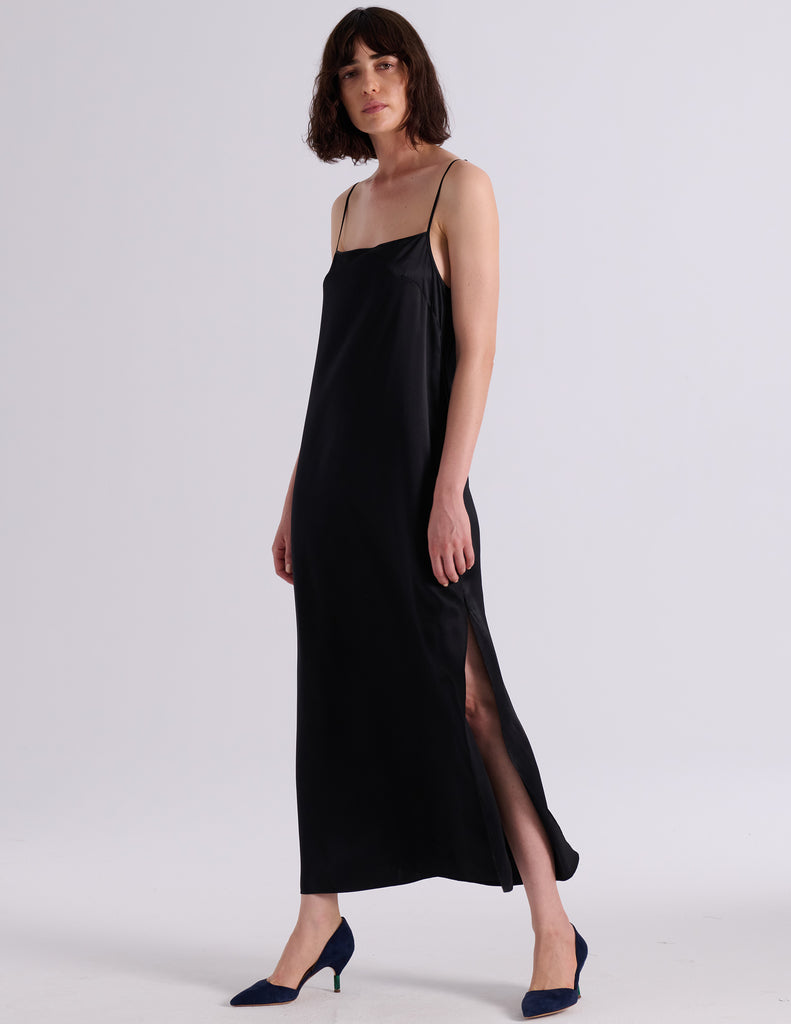 A woman modeling the Araks Vika slip in Black against a light gray studio background.