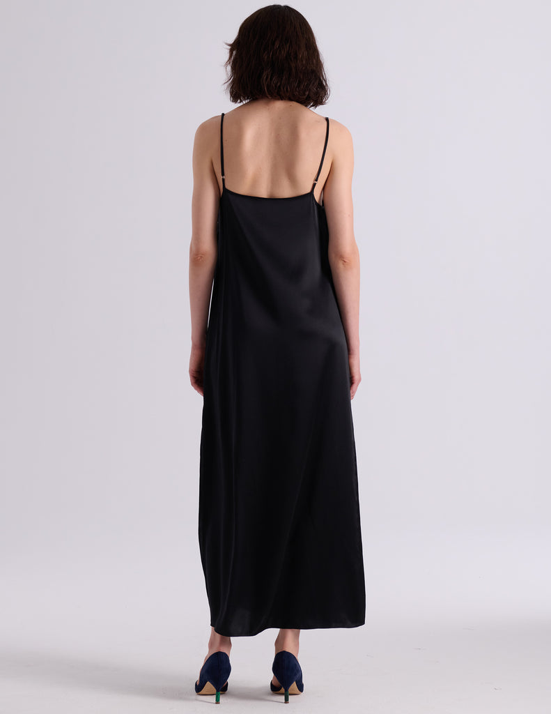 A woman modeling the Araks Vika slip in Black against a light gray studio background.