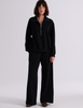 A model wearing the Araks Vivienne black half-zip sweatshirt and matching Vero wide-leg sweatpants, standing against a light gray studio background.