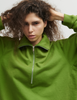 Close up of a model wearing the Araks Vivienne Sweatshirt in the shade Moss. 