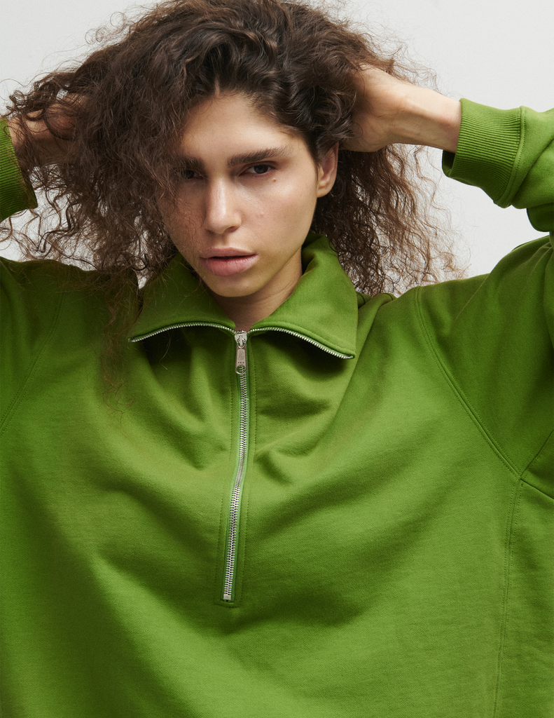 Close up of a model wearing the Araks Vivienne Sweatshirt in the shade Moss. 