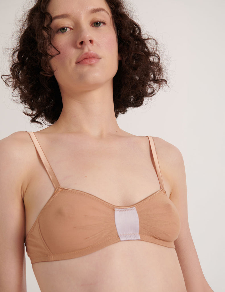 Woman wearing an Araks Cotton  in  beige bralette against a plain background