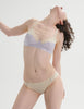 Woman wearing an araks cotton lavender bra and cream underwear on a plain background