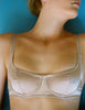 Close-up of a Araks Silk Underwire bra worn by a person against a blue background