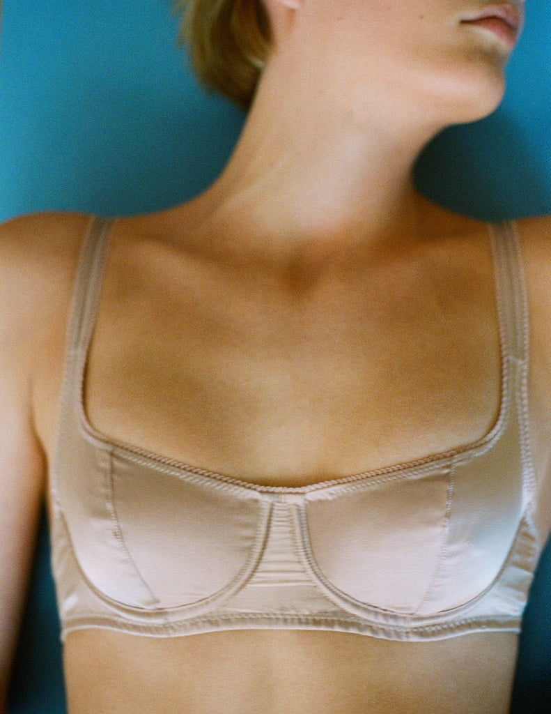 Close-up of a Araks Silk Underwire bra worn by a person against a blue background