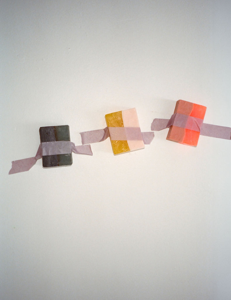 Three colorful square Araks handmade soap on a white surface