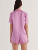 A back view of a model in the araks shiny silk charmeuse shelby pajama top and tia boxer in mauve purple