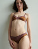 Woman wearing an Araks silk brown bralette and panty set against a plain background