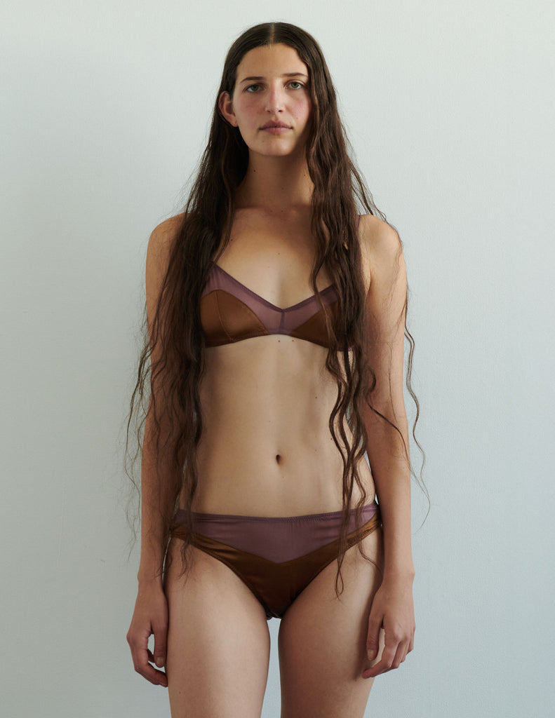Woman wearing an Araks silk brulee  brown panty against a plain background